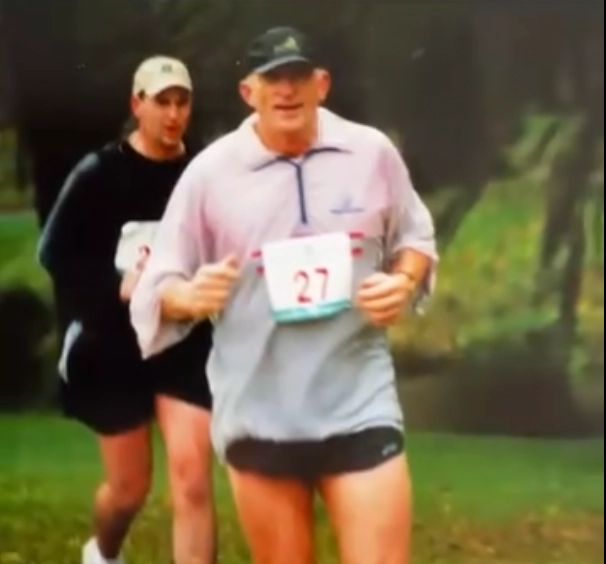 Stephanie’s father Donn running in a race, wearing a numbered bib, embodying energy, determination, and resilience.