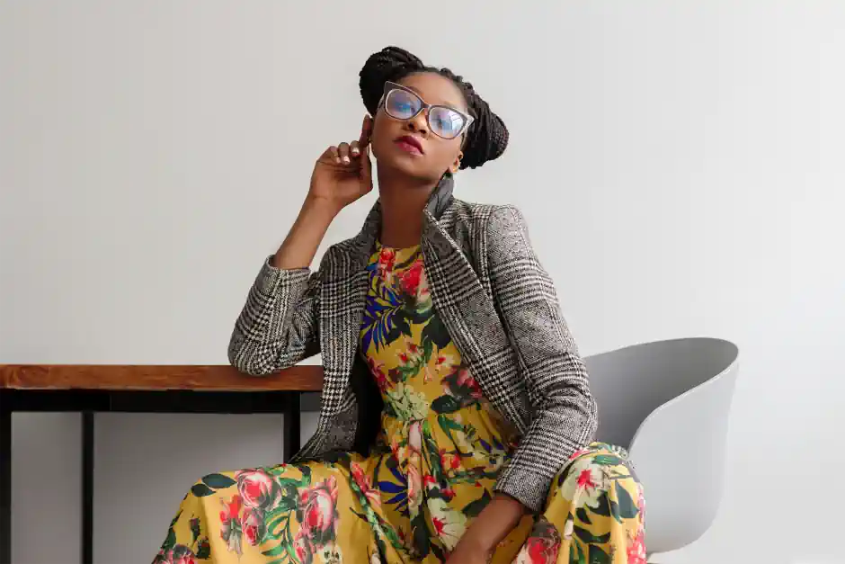 Woman wearing a vibrant floral dress paired with a checked blazer, blending feminine softness with structured tailoring in a modern, expressive style.