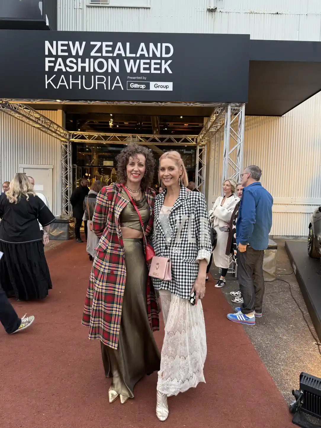 Stephanie Rumble and Mel Radford-Brown pose together outside New Zealand Fashion Week, dressed in bold statement outfits.
