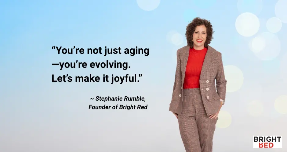 Stephanie Rumble, founder of Bright Red, stands confidently in a checked suit and red top beside a quote that reads, “You’re not just aging—you’re evolving. Let’s make it joyful,” against a soft blue background.