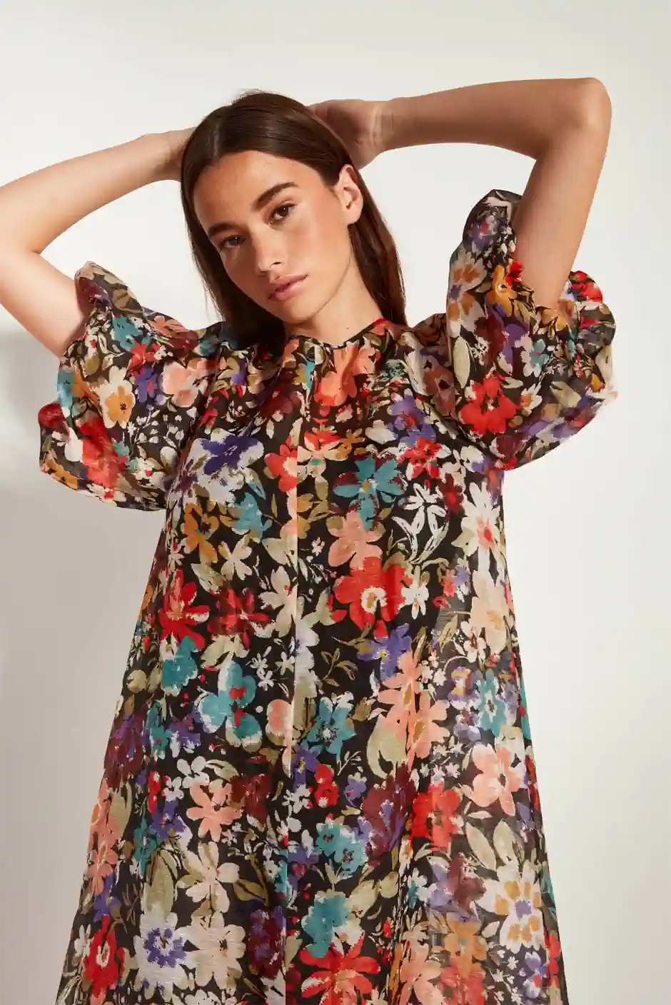 Woman wearing a flowing floral dress with sheer puff sleeves, showcasing the soft, romantic and graceful look of the feminine style personality.