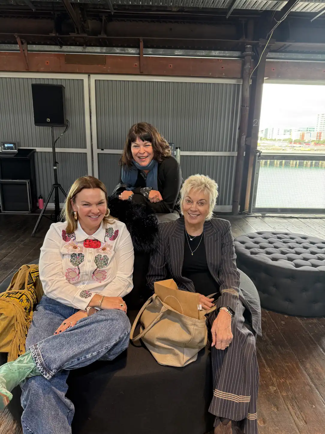 Rachele Davies, Dame Pieter Stewart, and her daughter Myken smiling together while seated after the Adrion Atelier fashion show.