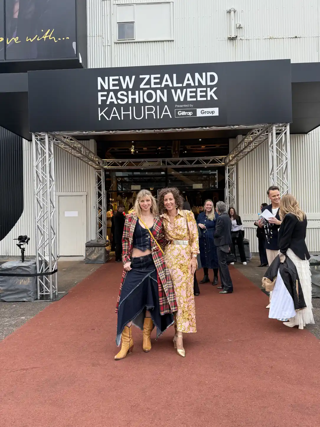 Stephanie Rumble with her daughter Poppy posing outside New Zealand Fashion Week, both dressed in bold, stylish outfits.