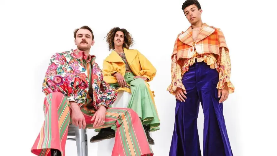 Three people wearing bold, colourful and exaggerated fashion pieces with eclectic patterns and vibrant fabrics, showcasing a highly creative style.