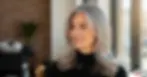 Smiling woman with naturally blended blonde and grey hair, representing the transition point between coloring and embracing grey.