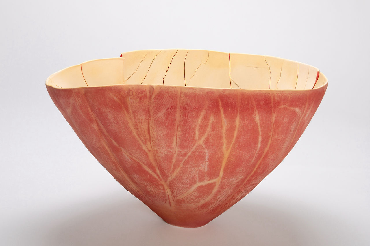 A red and yellow ceramic bowl with veining and cracks