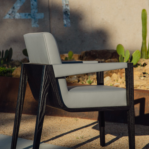 An image of a contemporary chair, made with an angular wooden frame and upholstered with leather.
