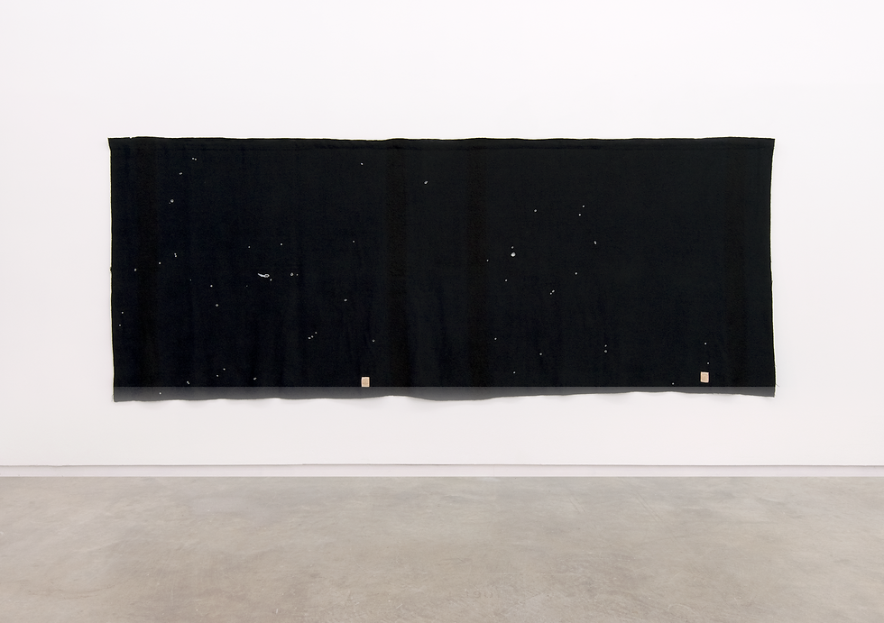 Image of a black wool blanket hanging from a white gallery wall.