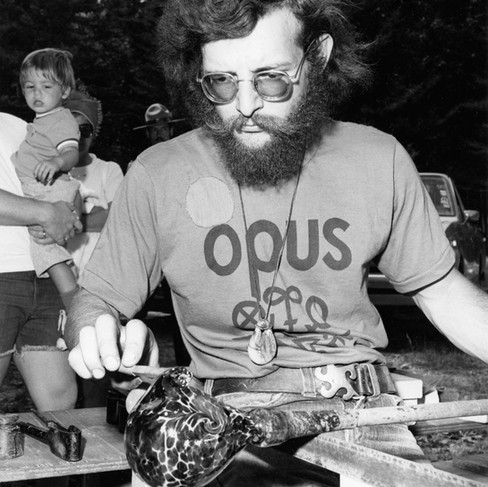 Glassblower Martin Demaine sculpts a hot blown glass vessel at Opus Craft Village