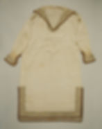 Image of a linen short with gold decorative embroidery around the neckline, cuffs, and hem.