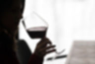 A young girl takes a sip of red wine in a restaurant.jpg