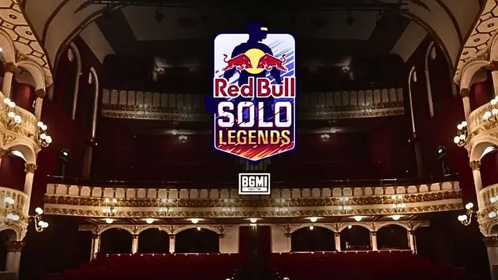 Interior of a grand theater with Red Bull Solo Legends and BGMI logos hanging above a dark stage and red seats.