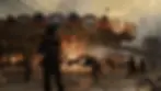 Armed soldiers in black gear near a burning carousel at dusk. Smoke rises against a cityscape backdrop with a bridge. Tense atmosphere. its from Battlefield 6 Video game.