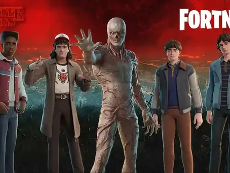 Characters from a game stand against a fiery red sky, including a creature reaching forward. "Stranger Things" and "Fortnite" text visible. Fortnite Players Can Unlock Dustin, Lucas, Will, Mike, and Vecna Skins Now.