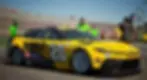 Yellow race car with "DEWALT" and "20" on side, parked on a track. Crew in green shirts in background. Bright, sunny day.