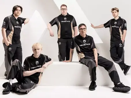 Five people in matching black and beige "Heretics" jerseys pose confidently against a white geometric backdrop. they are Team Heretics, the winner of the 2025 VALORANT Esports World Cup.
