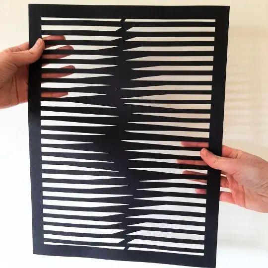 Miniature : illustration abstraite découpée sur papier noir tenue à la main