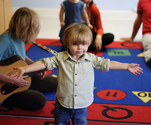 toddler with arms stretched out in a music class