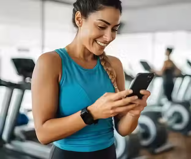 mulher na academia olhando notificação no celular
