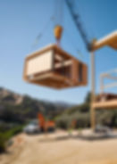 A modern elegant prefab home unit being craned down onto a building site in malibu over a pool.jpg