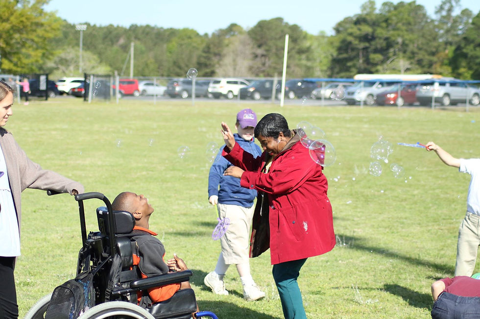 A PEC Teacher and students enjoying the bubble activities during adaptive field day.