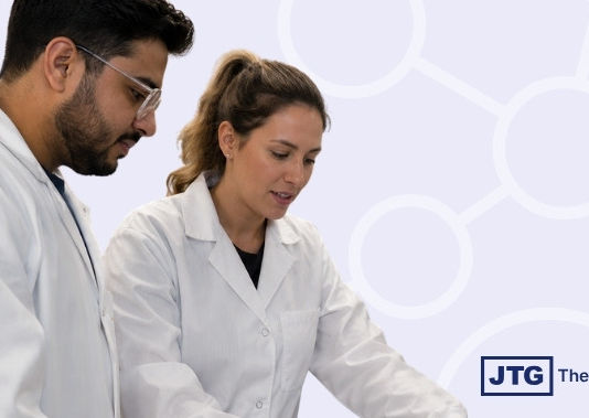 Two laboratory professionals in white coats review information together against a light background with subtle laboratory imagery.