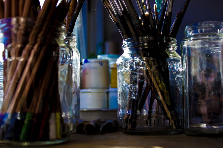 Photo at sunset of glass jars full of paintbrushes