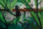Street art painting where dark silhouetted children play on gray concrete behind transparent green leaves with rusty industry