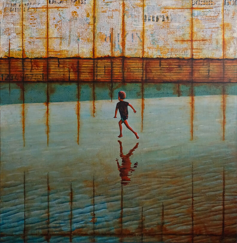 A boy is running across the beach through green water with rust-coloured patches, with rusty wall bearing text in background