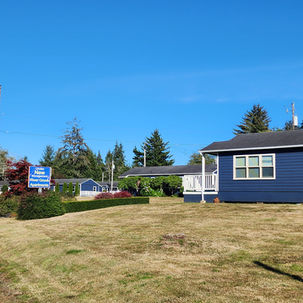 Photo of entrance to River Grove Apartments. Shows apartments buildings newly painted deep blue.