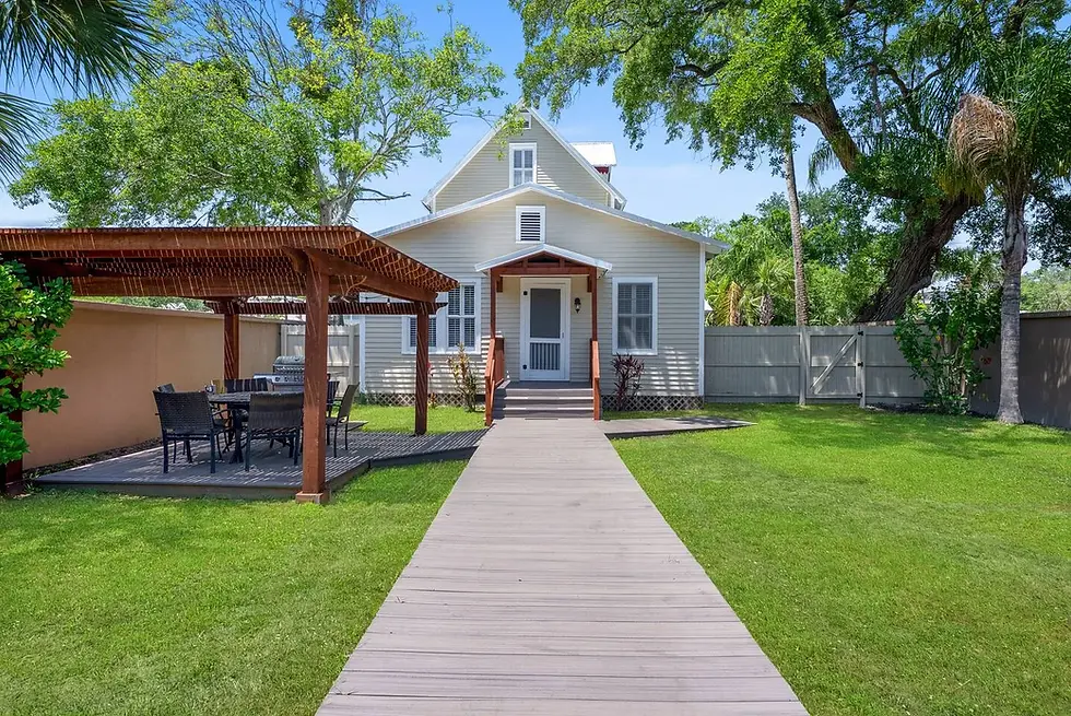 Historic white cottage exterior with mature oak trees and patio in St. Augustine