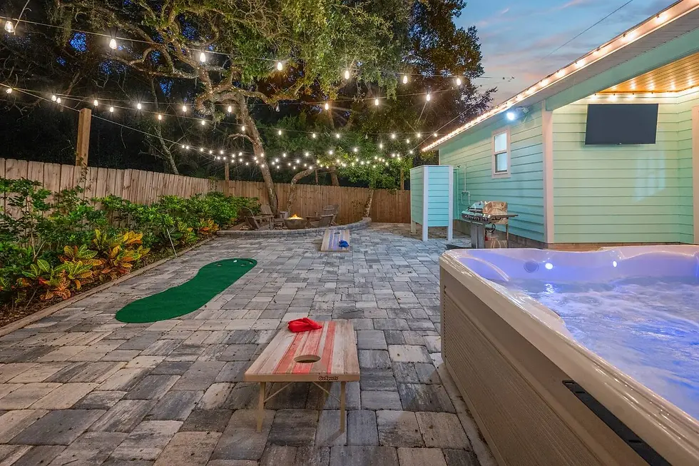 Backyard hot tub with string lights and games at St. Augustine vacation rental at dusk
