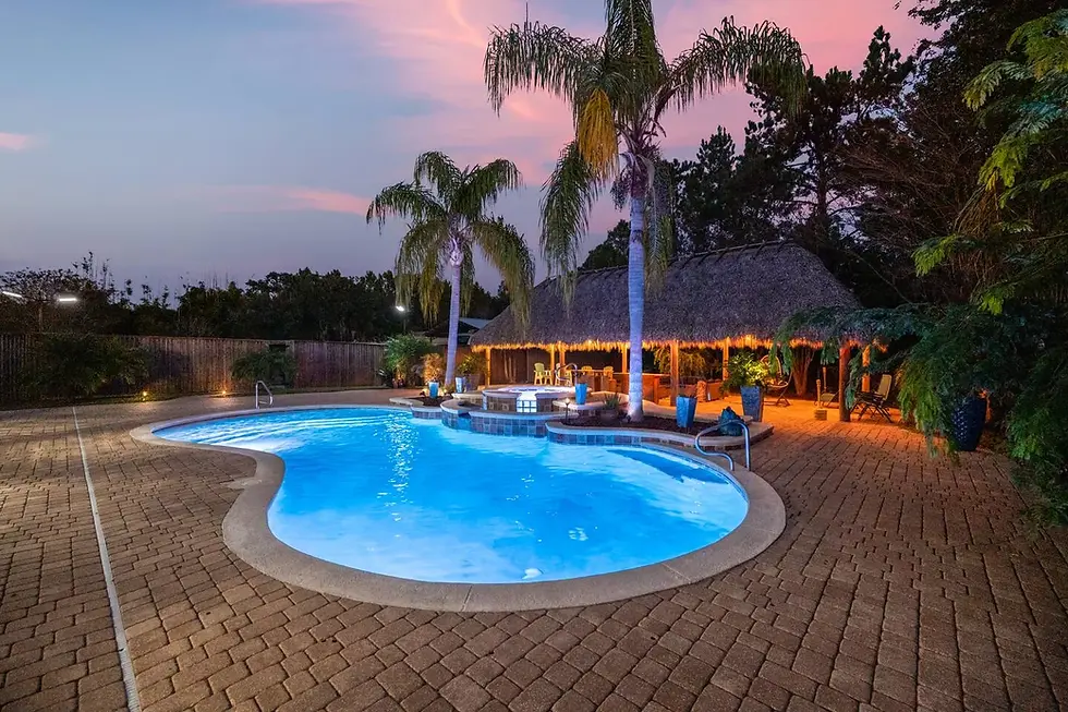 Resort-style pool with illuminated hot tub and tiki bar at twilight in St. Augustine vacation rental