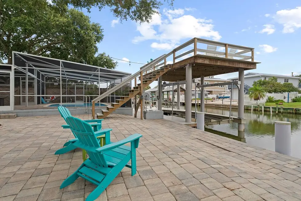Waterfront patio with turquoise Adirondack chairs and dock in St. Augustine property