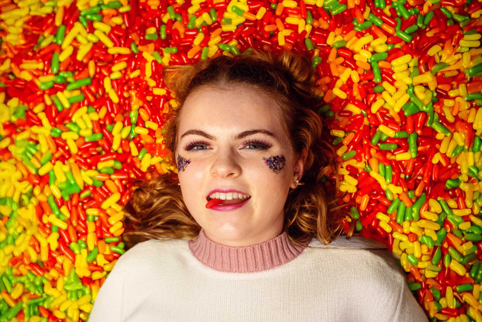 Senior Rep with one red Mike & Ike in her mouth with her head in a lot of Mike & Ikes