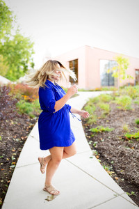 A senior girl get dizzy twirling in her blue dress to get some fun movement into her picture