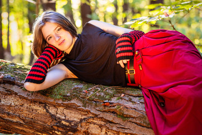 Black and white photo of a senior girl laying on a log smiling at the camera