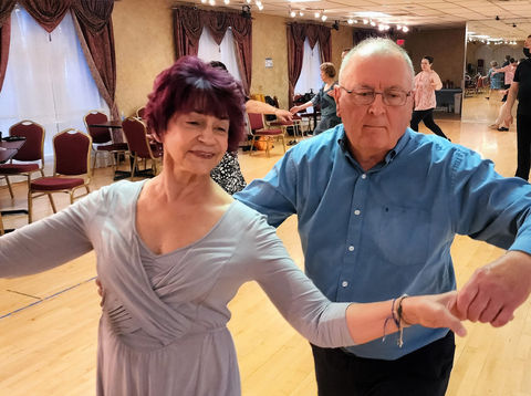 Advanced ballroom dance couple smiling while dancing.