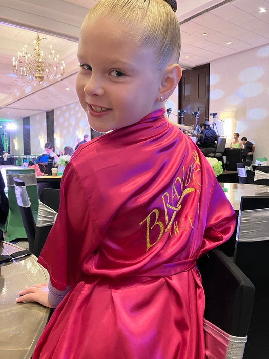 Young amateur student in a Bravo Aruba jacket smiling at a competition.

