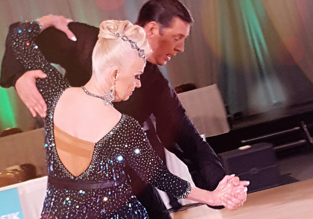  Pro-Am couple performing at ballroom dance competition.