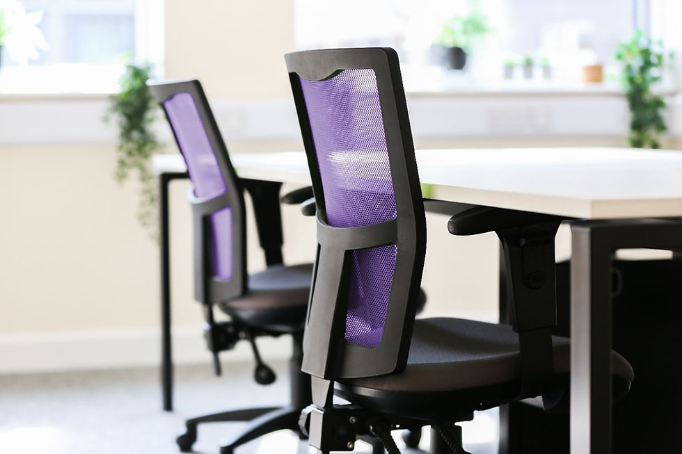 Two office chairs with purple mesh backs are next to a white table. The room is bright with plants on the windowsill.
