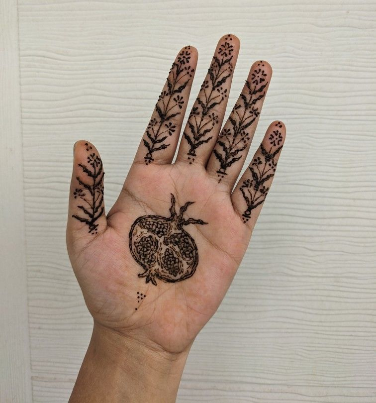 Front-hand mehndi design featuring a bold pomegranate illustration