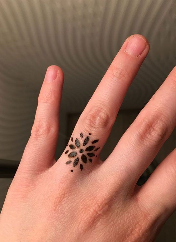 Small flower petal henna design on the ring finger.