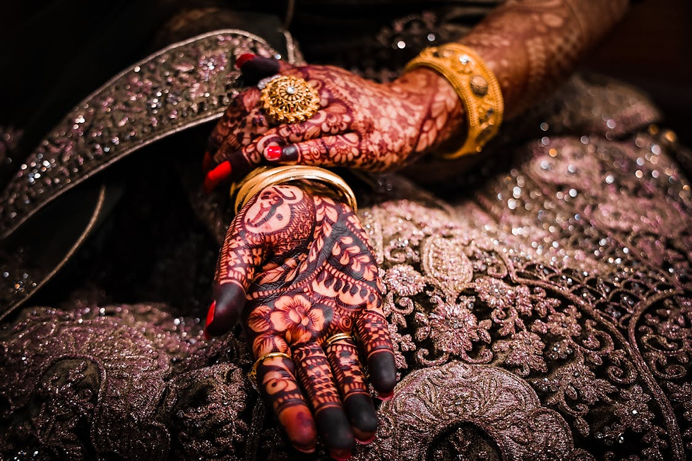 Front hand mehndi with floral center, solid fingertip fill, and fine detailing, shown resting on an ornate embroidered bridal lehenga