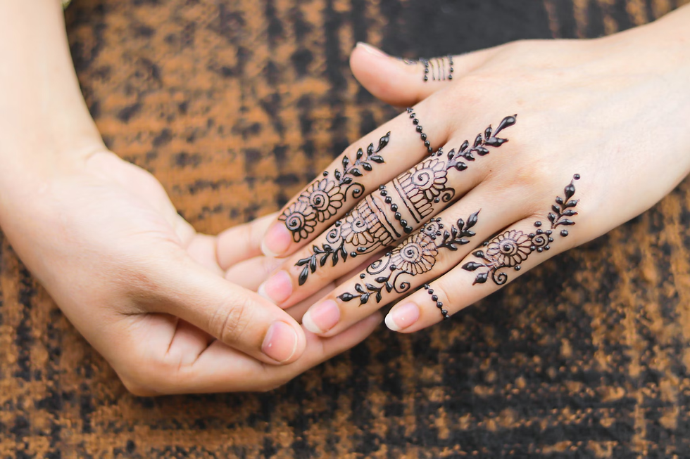 Close-up of fingers decorated with simple back hand mehndi design featuring floral motifs, leafy vines, and dotted ring patterns