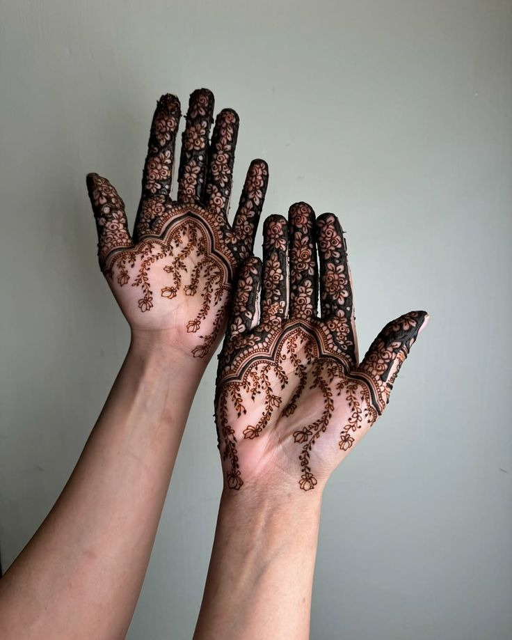 Palm mehndi with fine vine details and full fingertip florals.