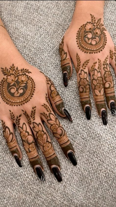 Back-hand mehendi with circular florals, leaf accents, and dark fingertip shading.