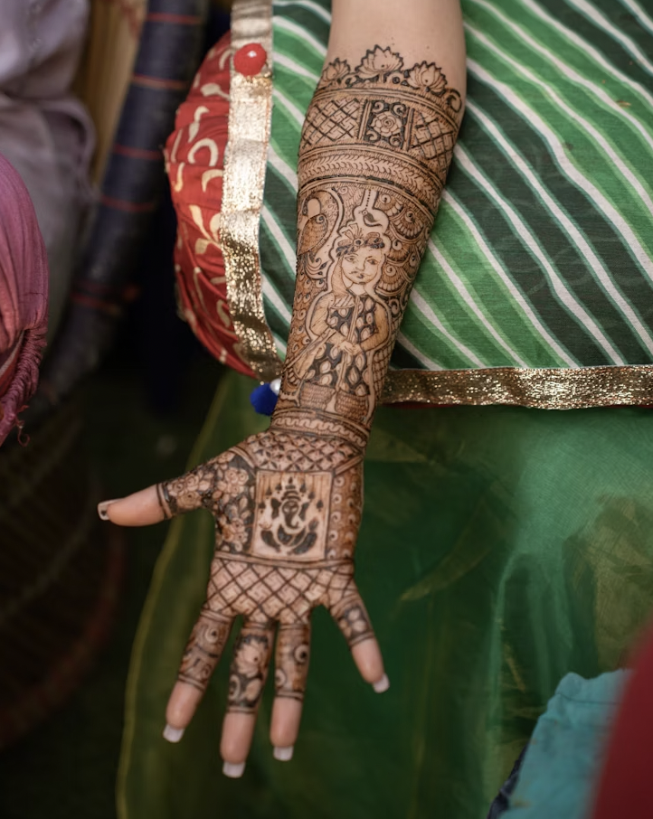 arm showing an elaborate front hand mehandi design featuring a deity figure