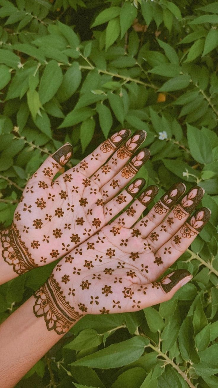Palms with dotted floral henna and patterned fingertips.