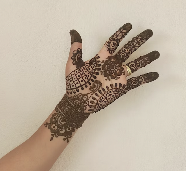 Palm extended to reveal a front hand mehndi design with dotted arches, floral circles, grid-style fills, and wrist detailing